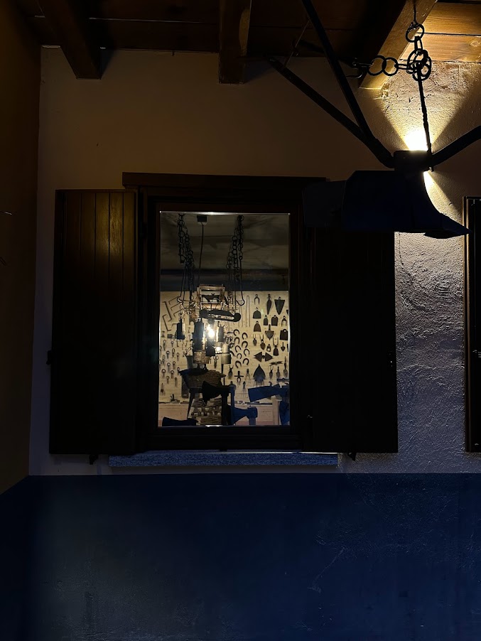 Fotografia di utensili da lavoro appesi ad una parete, vista attraverso una finestra